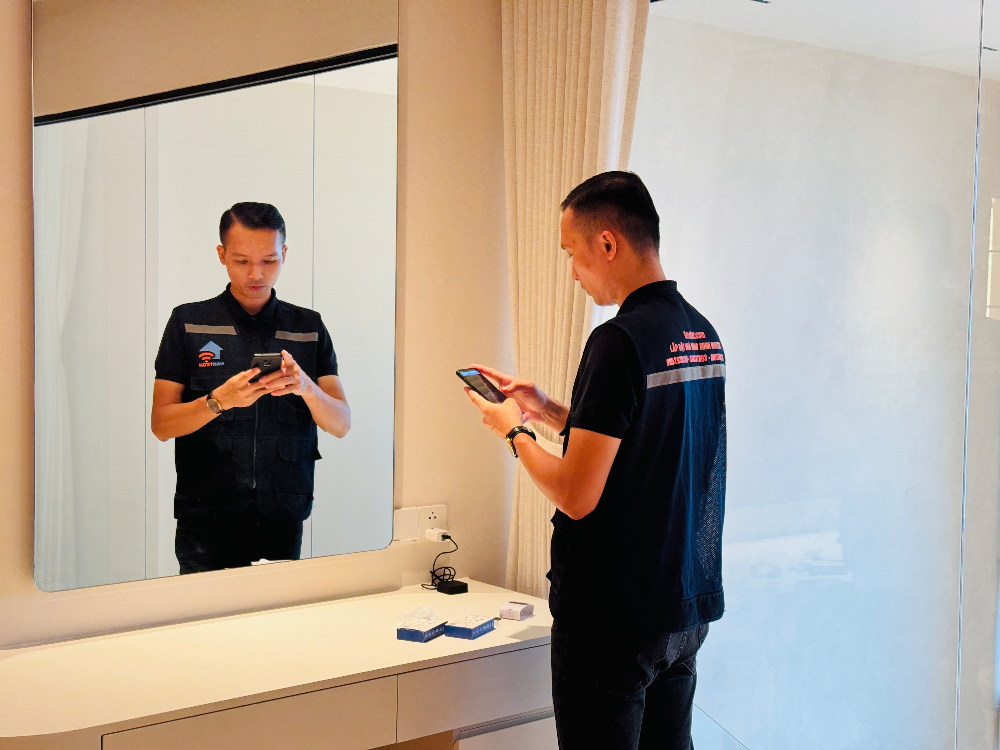 Người đàn ông đứng trước gương trong phòng tắm nhìn điện thoại